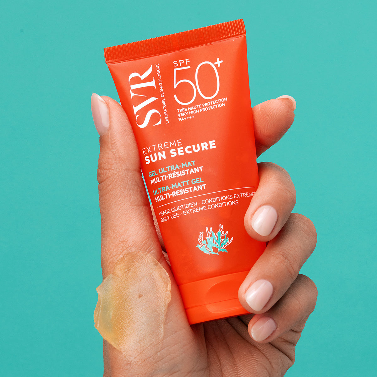 Main tenue en main d'un tube orange SVR Sun Secure SPF50+ avec une texture gel transparente sur la peau, fond bleu.