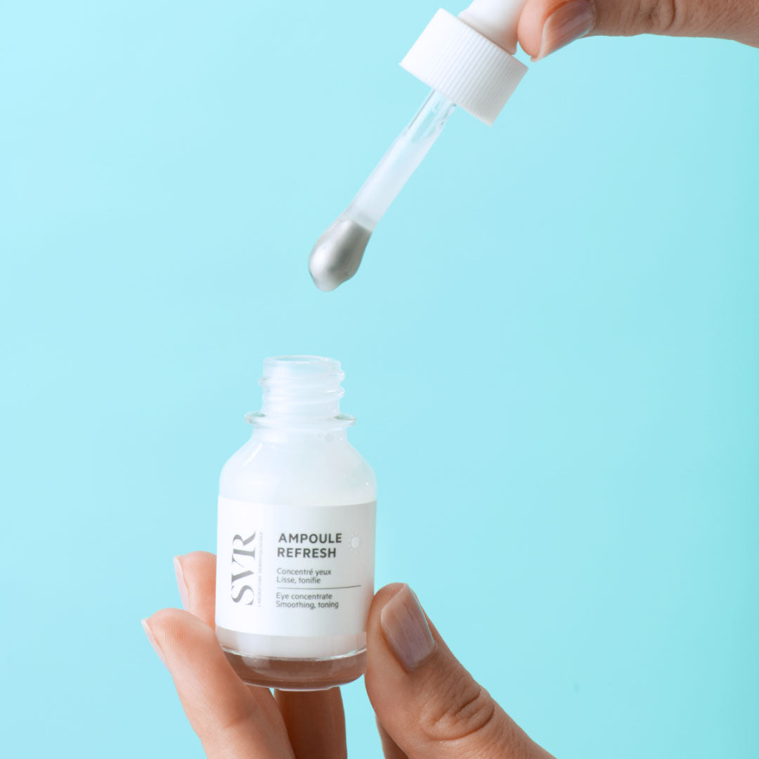 Sérum contour des yeux SVR Ampoule Refresh avec pipette massante métallique sur fond bleu clair.