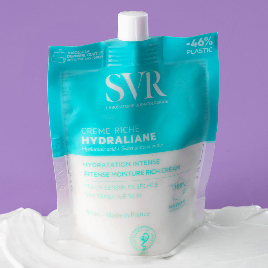 Poche éco-conçue SVR Hydraliane Crème Riche 50ml sur une texture crème blanche, fond turquoise et blanc.