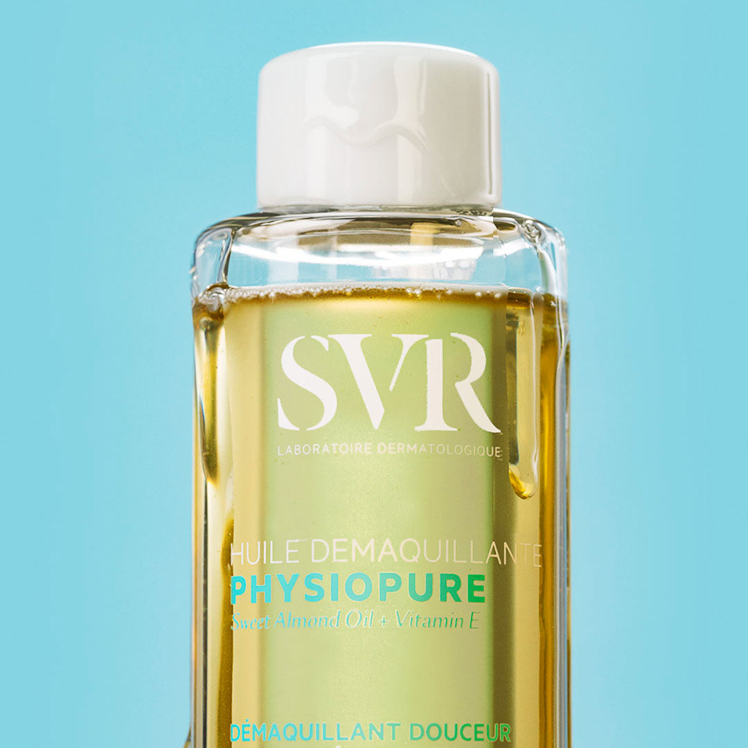 Flacon transparent d'huile démaquillante SVR Physiopure avec bouchon blanc sur fond bleu clair.