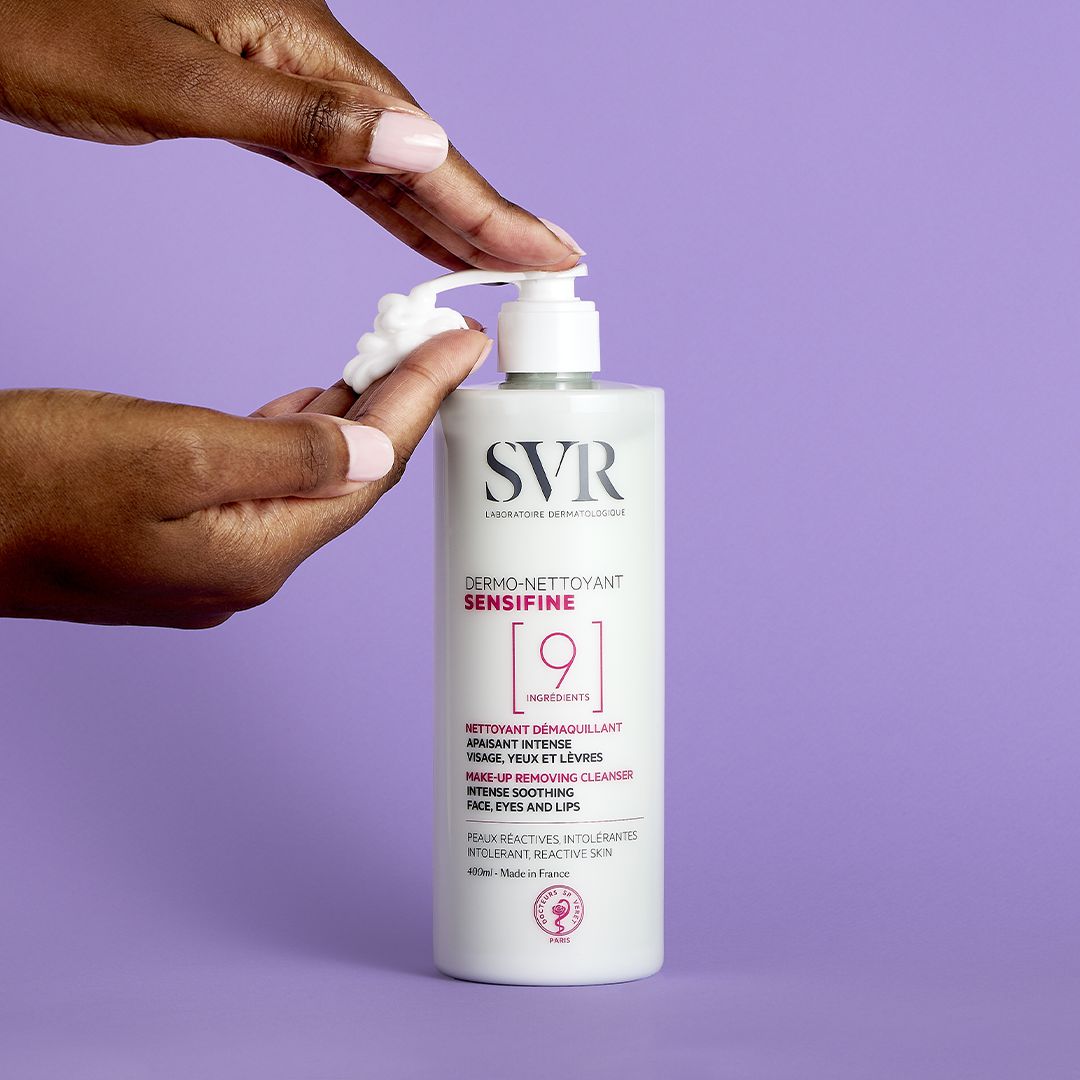 Flacon pompe blanc de nettoyant SVR Sensifine 400ml avec texture gel crème sur un fond violet.