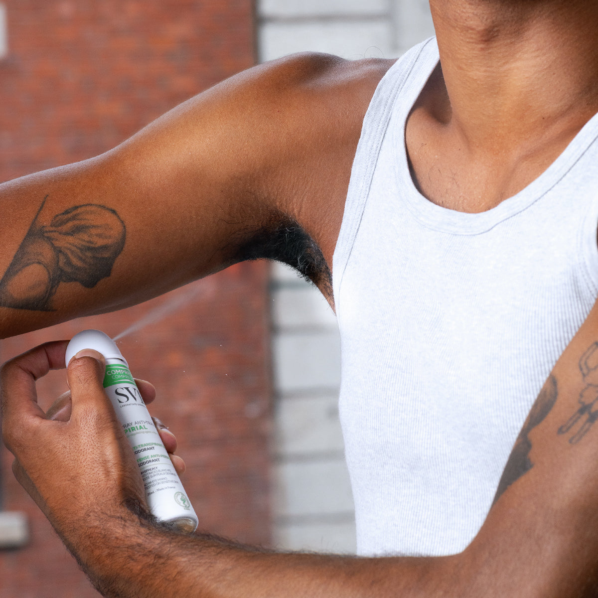 Homme utilisant le spray anti-transpirant compressé SVR Spirial blanc et vert sur son aisselle.