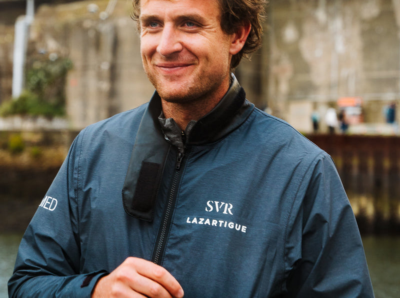 Tom Laperche, skipper du trimaran SVR-Lazartigue, portant une veste technique devant la base sous-marine de Lorient.