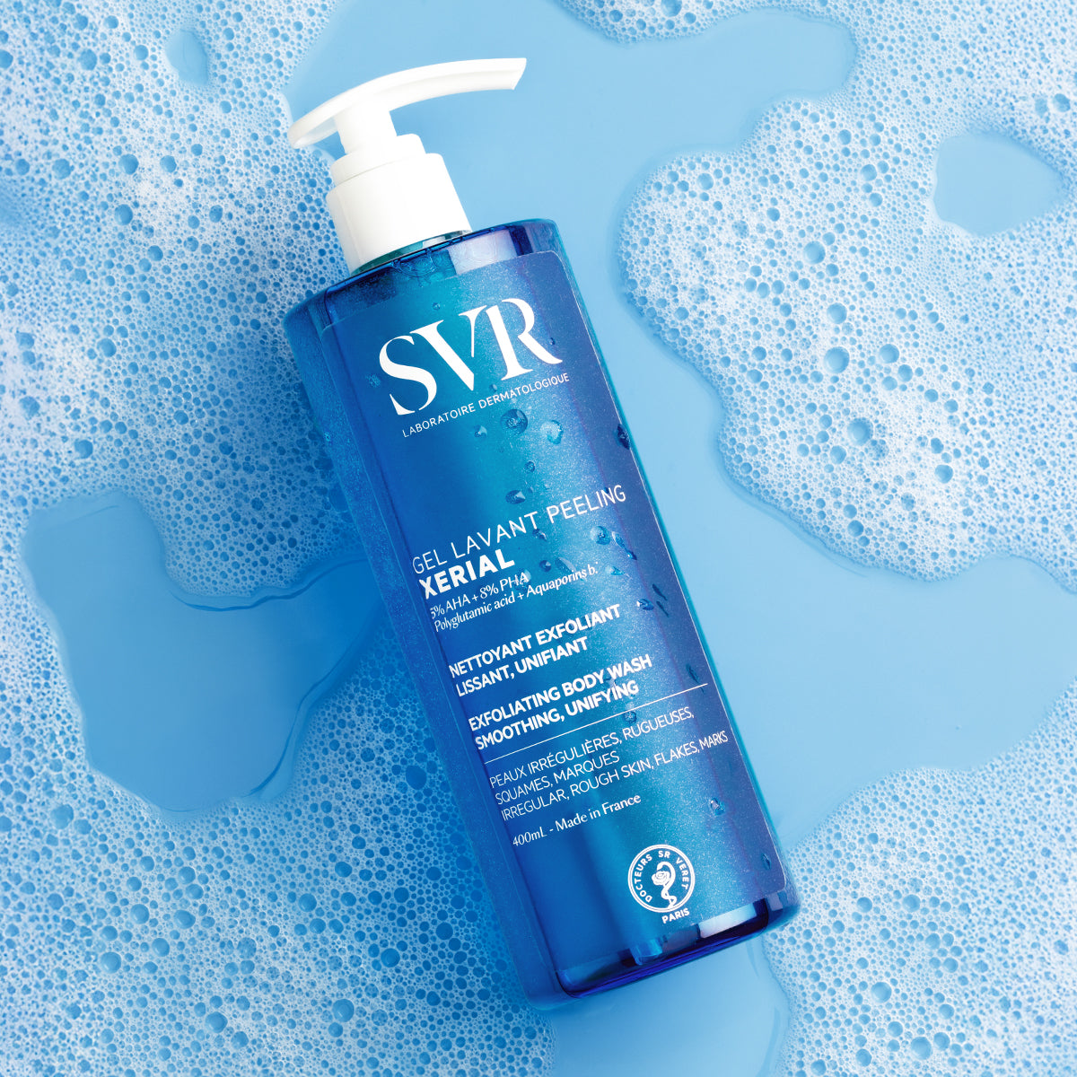 SVR Xerial Gel Lavant Peeling 400ml bottle with white pump dispenser, set against a blue background with soap bubbles.
