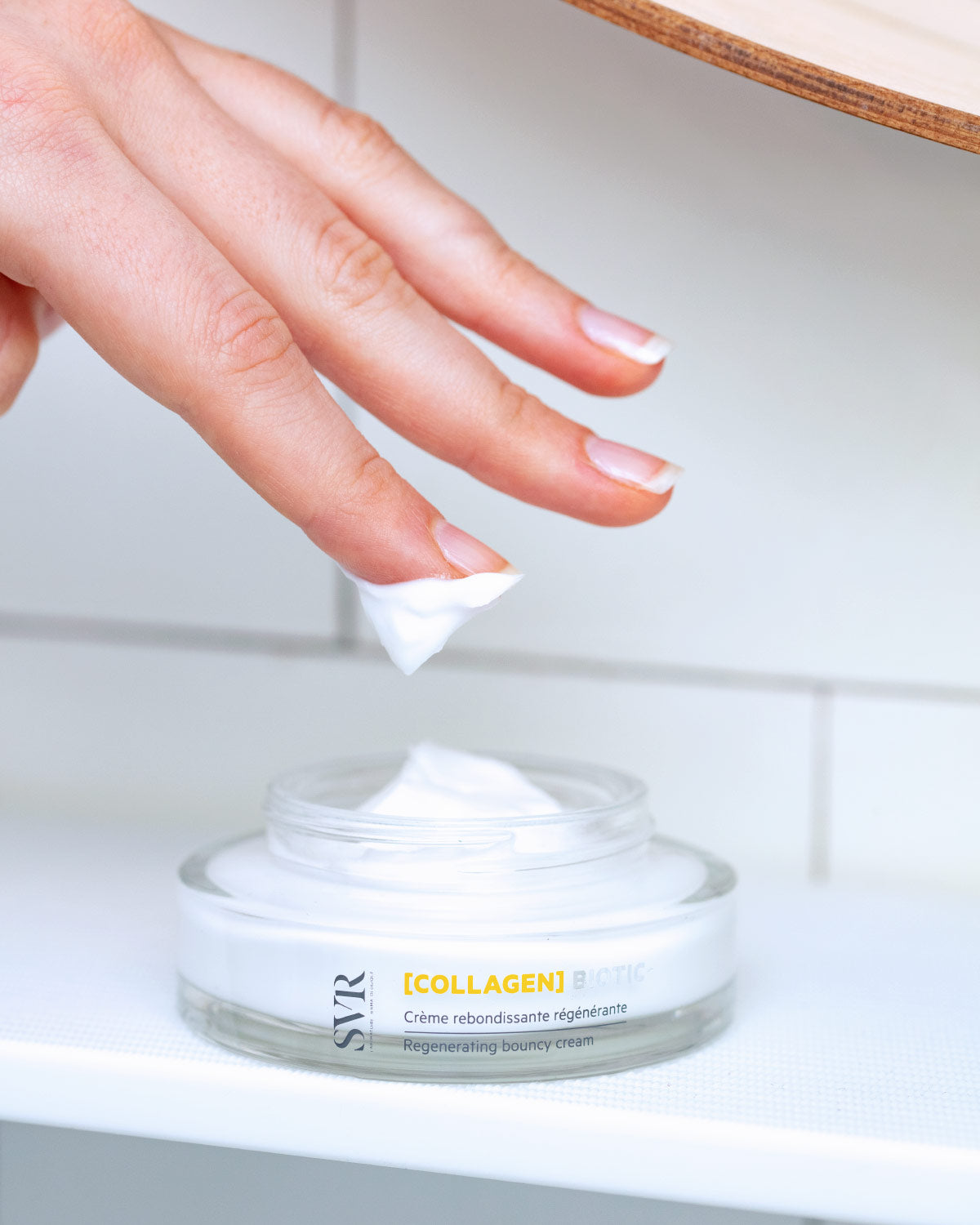 Crème régénérante SVR Collagen Biotic dans un pot en verre avec une texture blanche onctueuse prélevée au doigt.