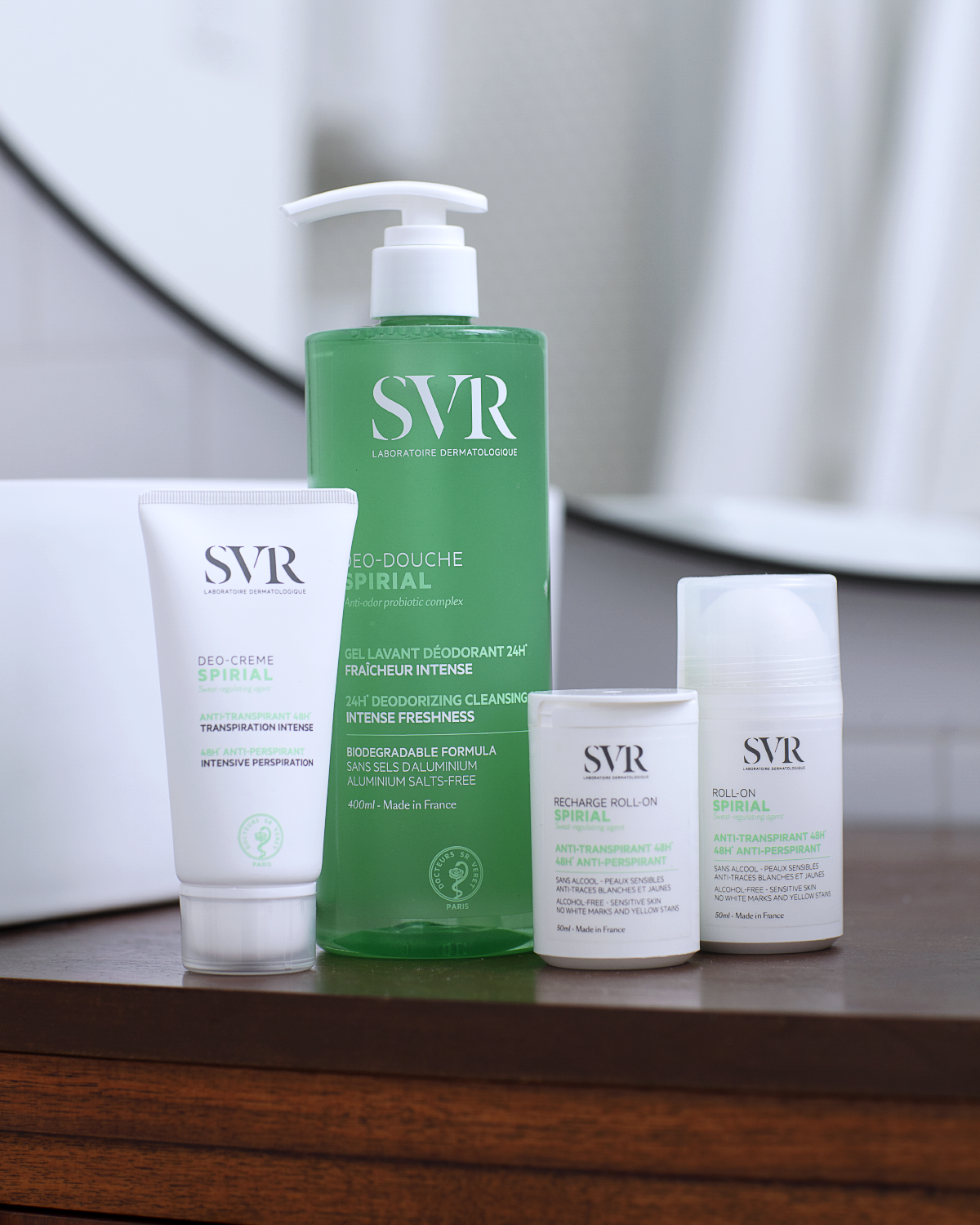 Gamme SVR Spirial : tube de crème déodorante, flacon pompe vert de gel lavant et deux déodorants roll-on sur une étagère.