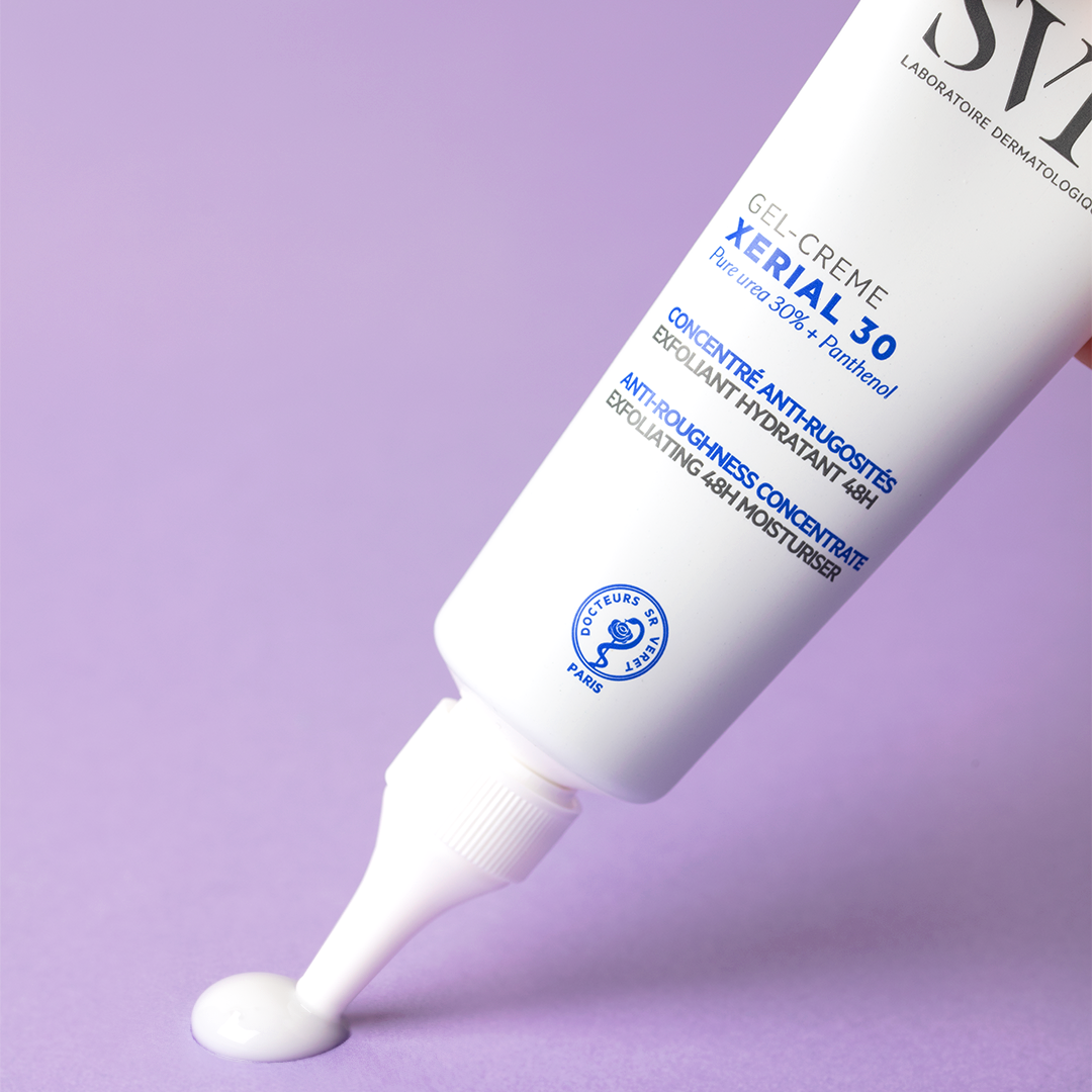 Tube blanc de gel-crème SVR Xerial 30 avec embout applicateur délivrant une noisette de crème sur fond violet.