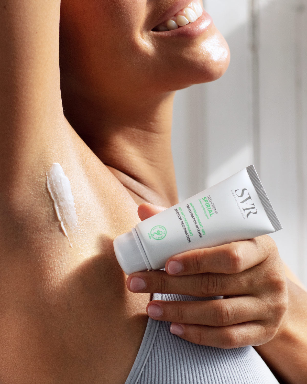 Femme appliquant la crème déodorante SVR Spirial blanche sur son aisselle pour une protection anti-transpirante.