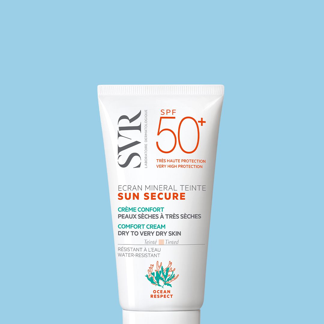 Tube blanc de crème solaire teintée SVR Sun Secure SPF50+ pour peaux sèches sur fond bleu clair.