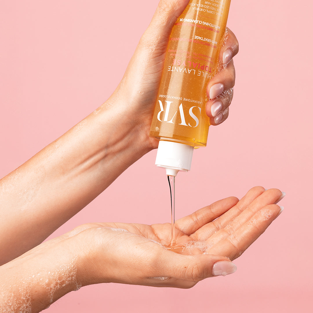 Huile lavante SVR Topialyse transparente versée dans une main sur fond rose, idéale pour la trousse maternité.