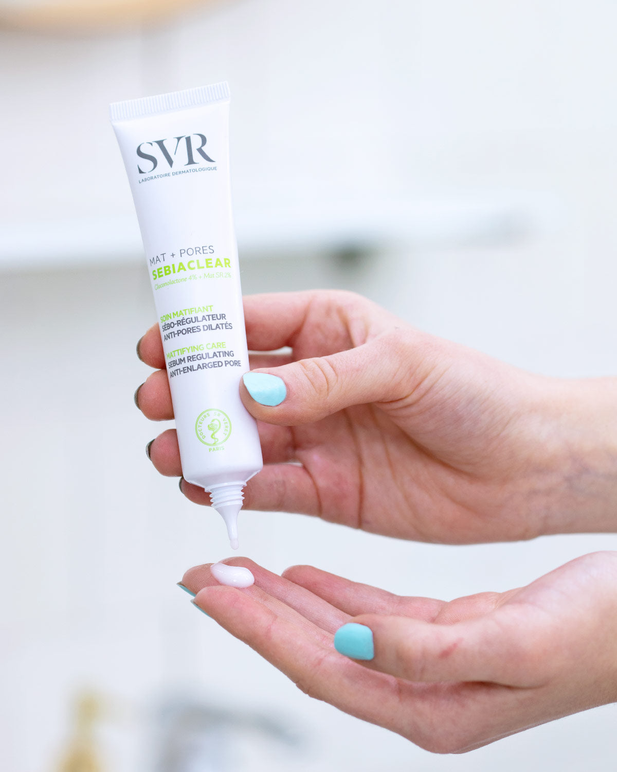 Tube de soin matifiant SVR Sebiaclear Mat+Pores blanc pressé dans la main pour appliquer une noisette de crème fluide.