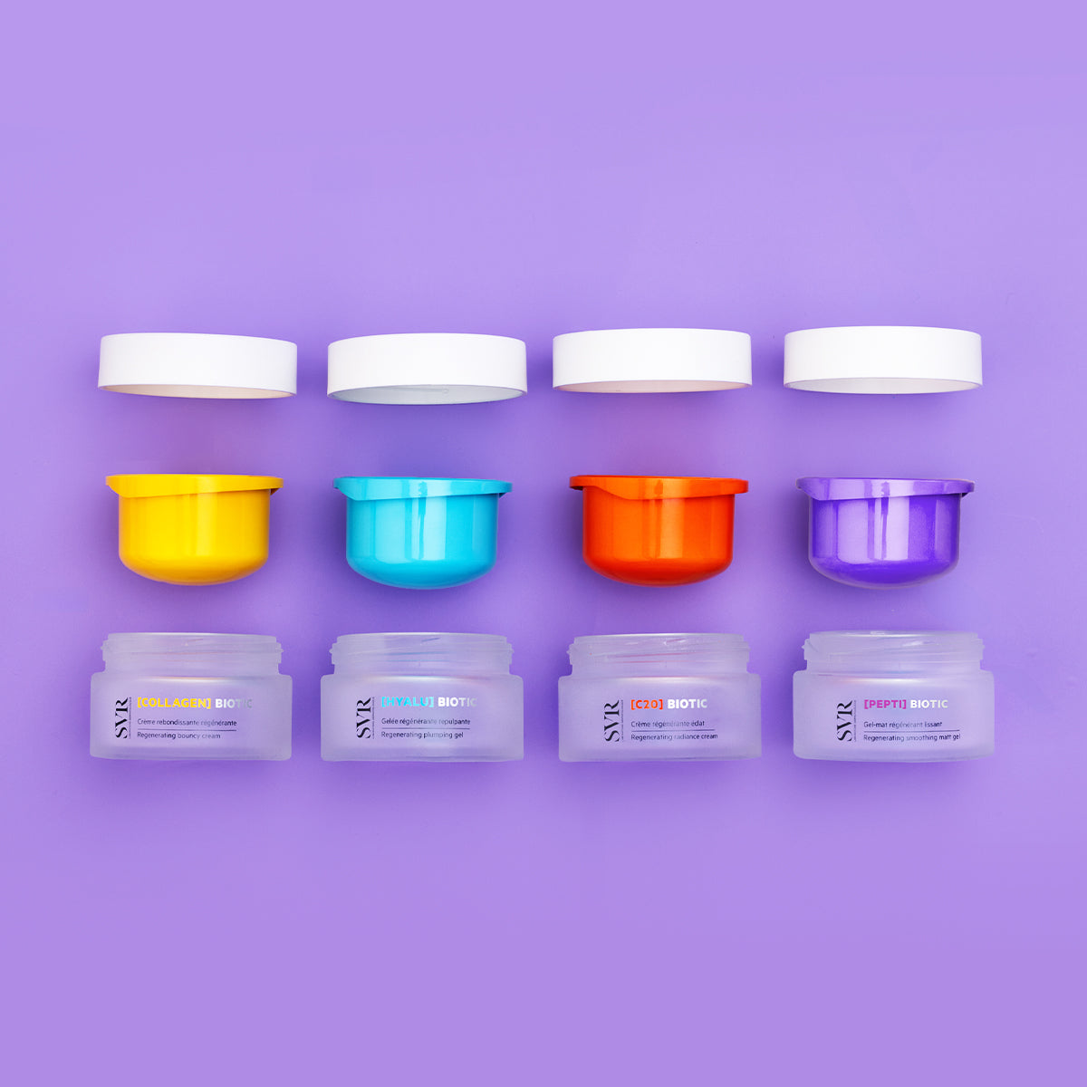 Quatre pots de crème SVR Biotic avec couvercles blancs et opercules colorés jaune, bleu, orange et violet sur fond lilas.