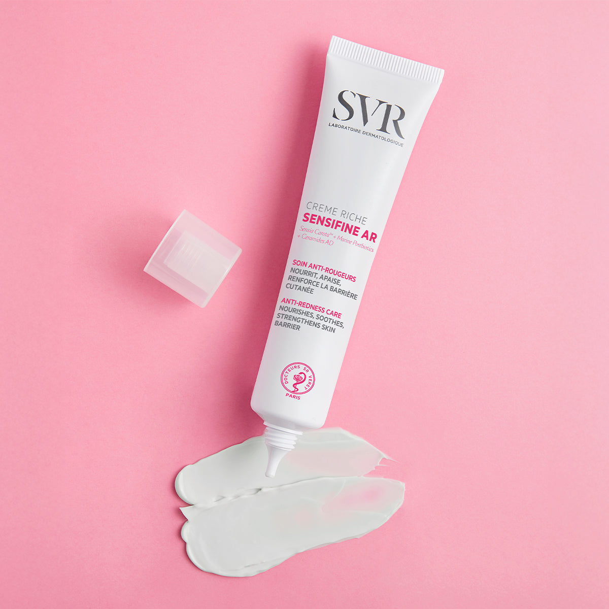 SVR Sensifine AR Crème Riche tube with white cream swatch on a pink background.