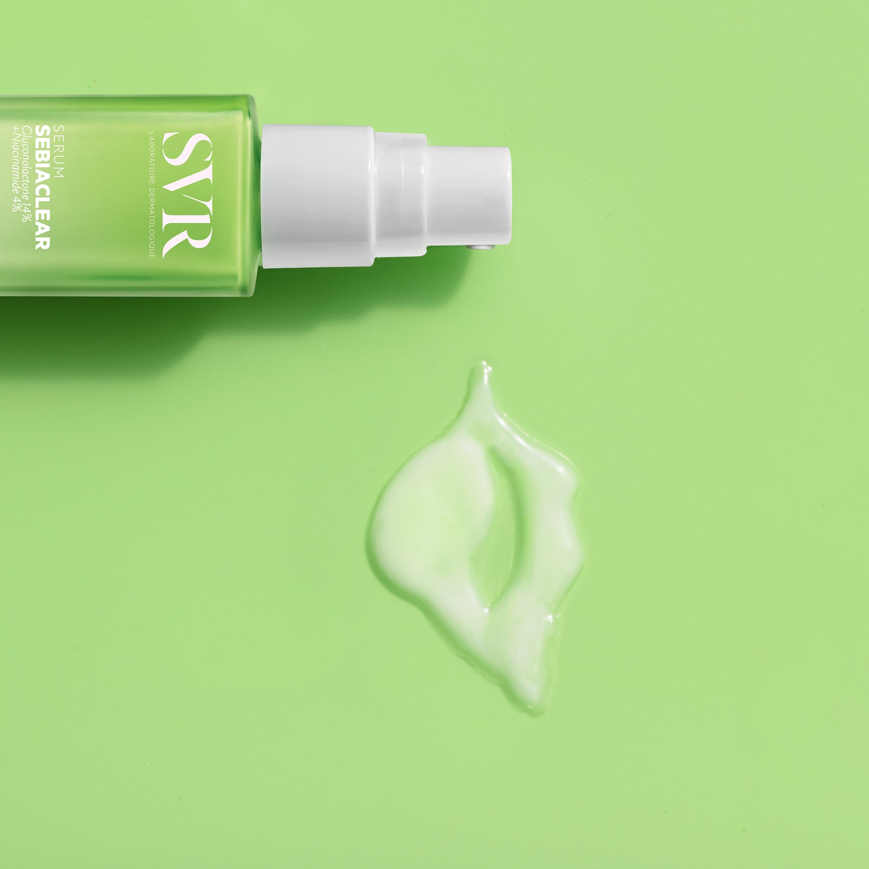 Flacon pompe SVR SEBIACLEAR Sérum vert avec une goutte de texture fluide sur fond vert clair.