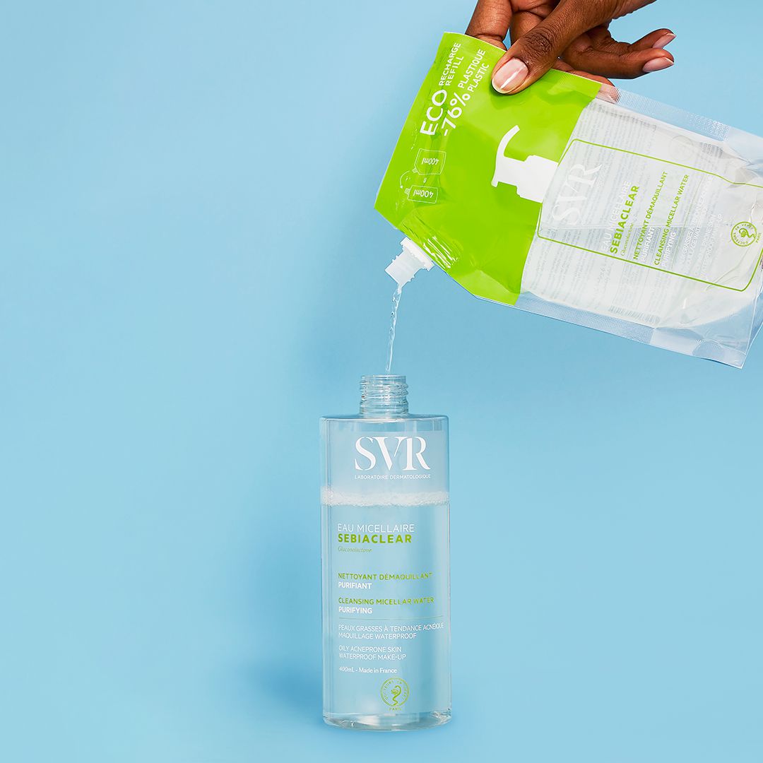 Recharge éco SEBIACLEAR SVR versée dans une bouteille transparente sur fond bleu clair.